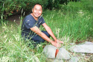 Michael Belmore ‘warms his hands’ over his outdoor installation ‘Outcropping,’ which can be seen at the Centennial Museum of Sheguiandah.