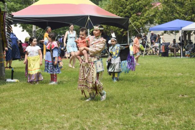 This jingle dress dancer shows the dance moves to her young charge.