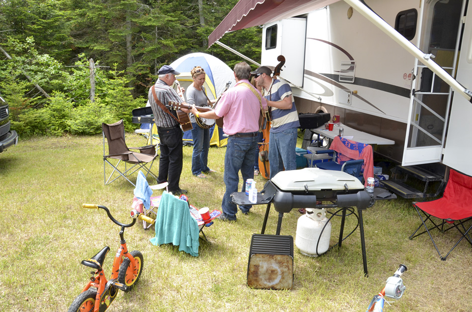 The Country Road 44 band rehearses outside their trailer, bringing in concertgoers of their own to listen in.