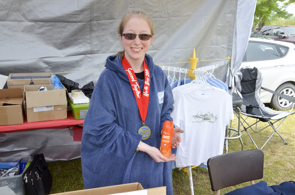 Rebecca Strain, gold medallist in  curling, sells bug spray to happy  festivalgoers, raising funds for Manitoulin Special Olympics.