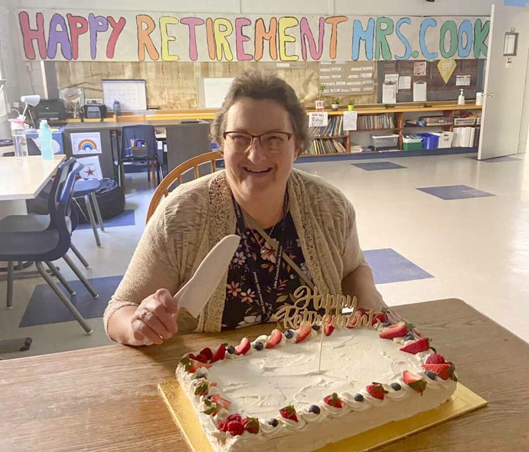 Little Current Public School Educational Assistant Bonnie Cook is retiring after 33 years of working with special needs students. The school held a party for Ms. Cook to congratulate her and she is pictured here ready to cut her cake. (The room on the other side of the camera is filled with clapping students.)