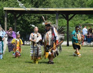 Head dancers Gmewin Migwans and Craig Fox share a few words while dancing under the warm early summer sun. photo by Michael Erskine