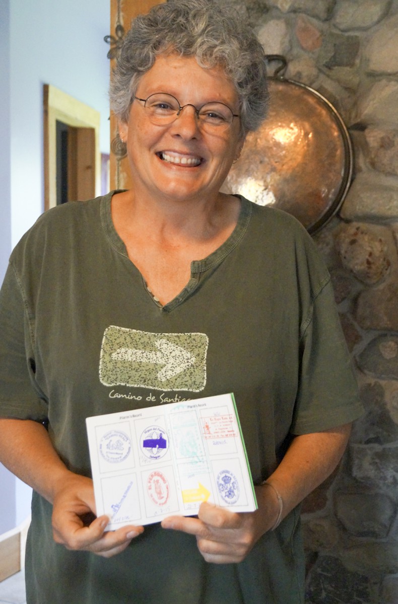 Anita proudly shows the “passport” style book that she carried with her through the Camino de Santiago pilgrimage which began in St Jean Pied de Port France. The stamps represent the different stops along the way.