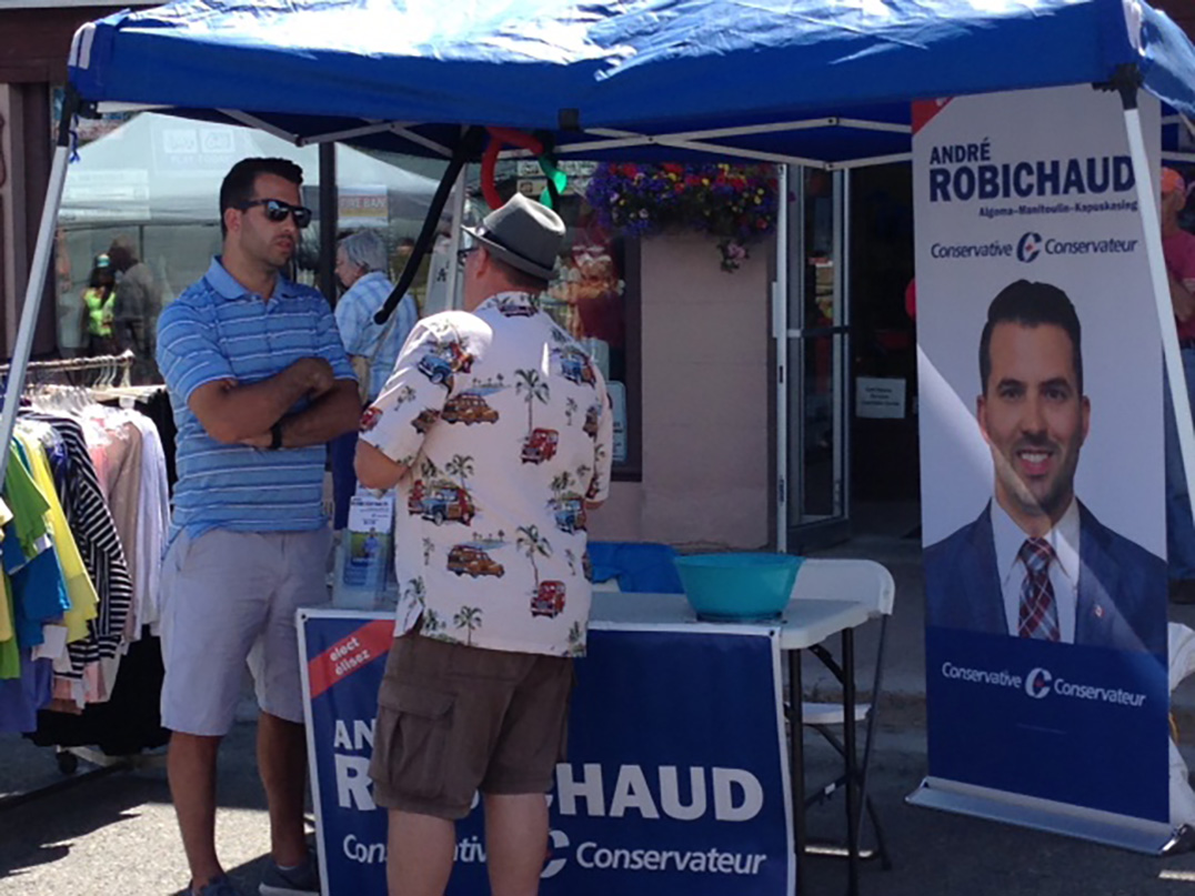 Federal Conservative candidate André Robichaud chats with a  voter from his Hawetaer post in downtown Little Current.