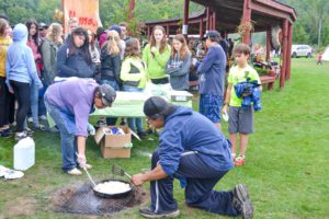 Mark and Patrica Panamick cook scone over an open fire while hordes of children patiently wait to sample.