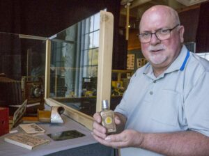 Dave Pulsifer, the vintage camera consultant for the ‘Snapshot in Time’ exhibit, has collected hundreds of cameras since grade school and many of these rare and original pieces are included in the displays. Here he holds a bottle of ‘Flash Powder’ that sometimes caused lethal explosions when used to illuminate photos in the 1890s. photos by Isobel Harry.