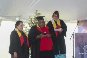 Kenjgewin Teg’s first Practical Nursing graduate Iosefo Taukei delivers his address on behalf of the Health and Wellness graduates. Kenjgewin Teg Director of Health and Wellness Whitney McGraw, left, and Dean of Post-Secondary Education Debbie Debassige (and master of ceremonies for the 2023 graduation), right, support Iosefo during his speech. photo by Veronica Roy