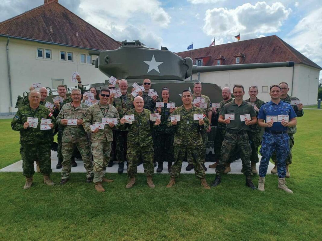 Security Assistance Group-Ukraine (SAG-U) J7 (Training) Team with post cards from the Little Current Royal Canadian Legion. The Team is made up of 14 Partner Nations including: Australia, Belgium, Canada, Finland, Germany, Great Britain, the Netherlands, New Zealand, Norway, Poland, Romania, Sweden, Ukraine, the United States.