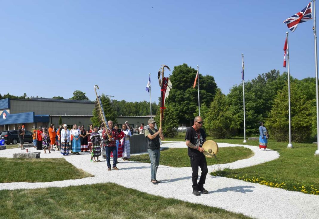 Family members of Missing, Murdered, Indigenous Women, Girls and Two-Spirited+ process to a new red granite monument unveiled at Whitefish River First Nation on National Indigenous People’s Day. photo by Michael Erskine