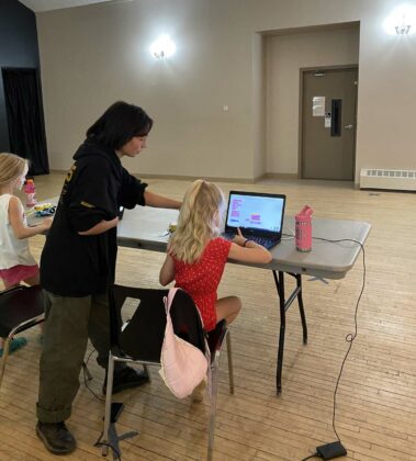 Robyn-Ashley helps a young student code.