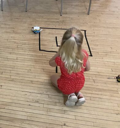 A young female student works on troubleshooting her robot.