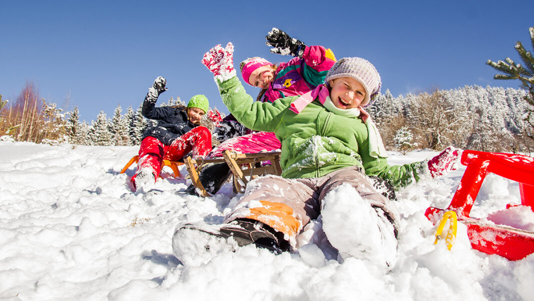 Happy children sledding at winter time.