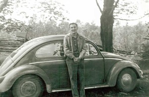 John Hodder poses in front of his first car a VW, May 1962 during his first year of teaching at Little Current Public School.