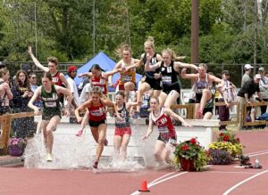 Manitoulin Secondary School’s Maren Kasunich, right and wearing the number one, leaps over a water obstacle in the steeplechase event at the OFSAA all-Ontario championships held in Ottawa last week. Maren placed fourth in all of Ontario and scored a personal best time in the process. photo by Darren Jermyn