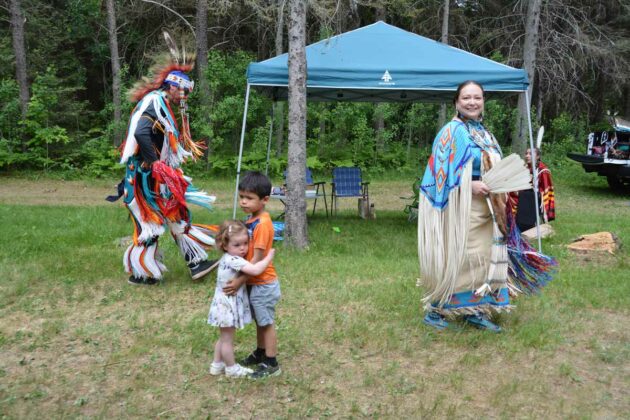 Julia and Noodin pause for a hug during an intertribal at the Sheshegwaning traditional powwow Saturday much to the delight of the dancers around them.