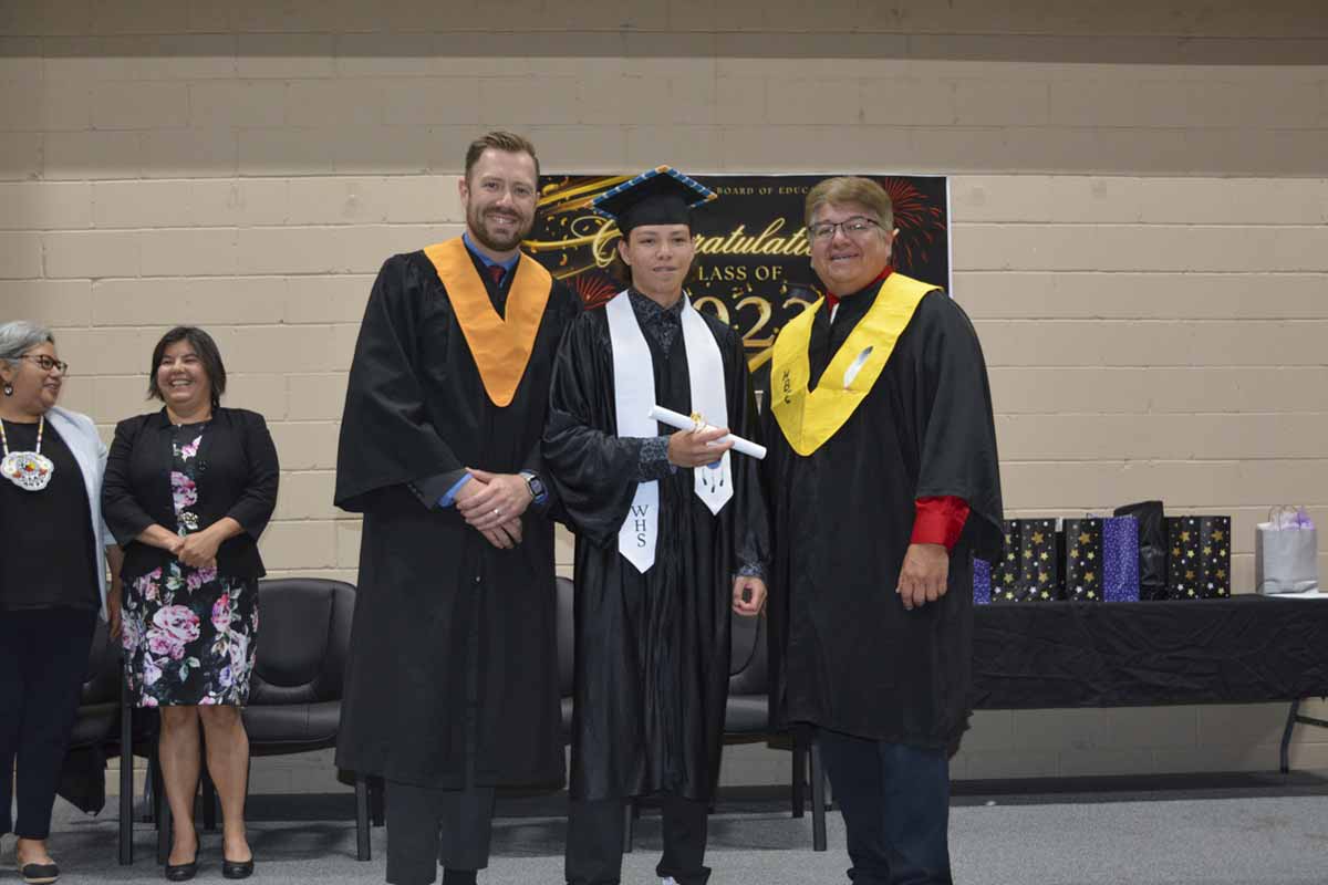 Vice-principal Cameryn Beaudry and Principal Harold Fox present valedictorian Jonas Assinewai with his diploma.