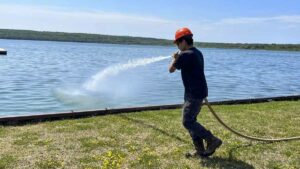 A wildfire firefighter trainee practices with a fire hose in Smith Bay.