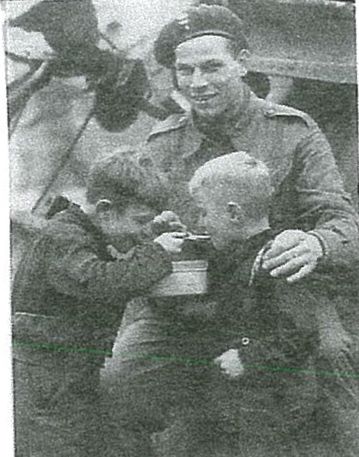 Hungry Dutch children accept food from a Canadian soldier.