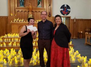 Father Paul Robson, centre, presents Dawn-Marie Jacko with gift certificates for taking on the candlelight concert series with the help of Audrey Ozawabineshi, right, and Ms. Jacko’s partner Rick Leedham and daughter Trinity. This is the third candlelight concert series to date in support of Holy Cross Church.