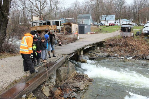 Dale Baker takes students on a tour of the clubs fish platform, outlining the process for raising walleye among other educational information.