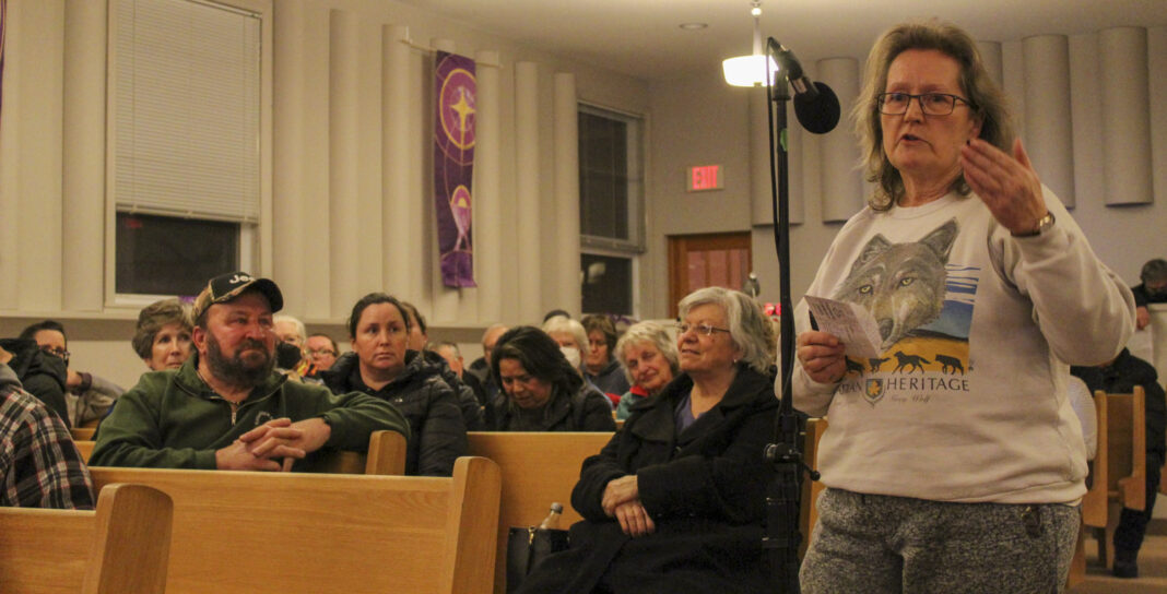 woman speaks at a microphone at a public meeting