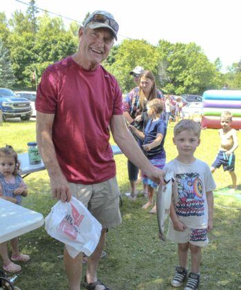 Five-year-old Noah Prevost of Dowling displays the fish he caught to Murray Orford, a member of the Gore Bay Fish and Game Club.