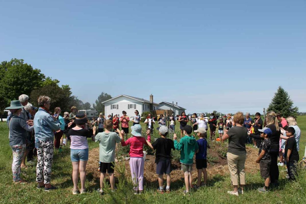 Students of Lakeview and CC McLean schools and members of the Western Manitoulin Community Garden gather in a group to listen to the song ‘O’Siem’ at the Heart Garden.