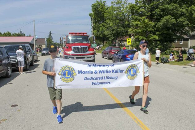 In memory of two hardworking dedicated members of the community! Nicky and Maddy Keller lead the Central Manitoulin Lions Club Homecoming Weekend and Manitoulin Ribfest parade with this banner. The two youngsters are the great grandchildren of Morris and Willis Keller, dedicated lifelong volunteers with the Lions club and the community, who passed away earlier this year.