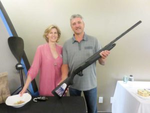 Birthday boy Ray Beaudry shows off the 12 guage semi-automatic shotgun he won at the gala and is flanked by Deborah Ramakko.