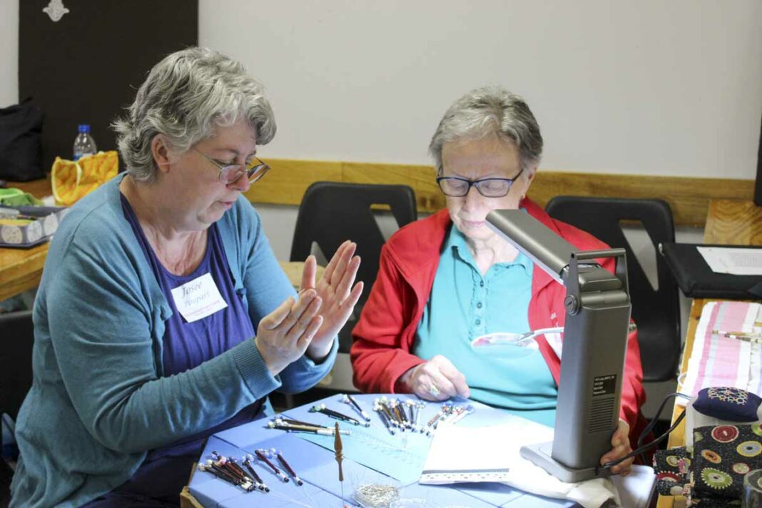 Lacemaker Joyce Poupart, left, helps instruct a fellow lacemaker at the annual Gore Bay International Lace Camp, held last week.