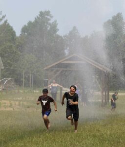 Cool it! Children of all ages were thrilled to get the chance to get wet and cool off from the scorching heat thanks to the M’Chigeeng Fire Department using their pumper truck to provide a ‘water falls’ that the kids could run under. photo by Tom Sasvari