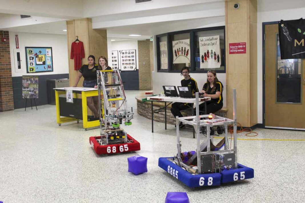 From left, MSS students Jocelyn Kuntsi, Alex Wilson-Zegil, and robotics team drive members Ryan Kuntsi and Nevaeh Harper present a demonstration of the team robot ‘Bumble Bee’ at a Manitoulin Metal robotics community appreciation dinner event.