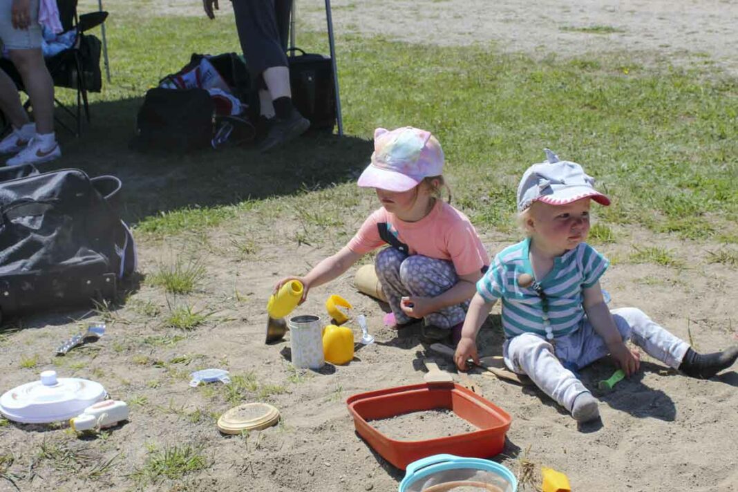 Two very young children are enjoying playing with toys in a sand box. photo by Tom Sasvari.