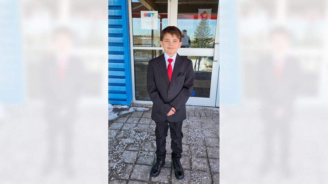 small boy in suit in front of tv studio