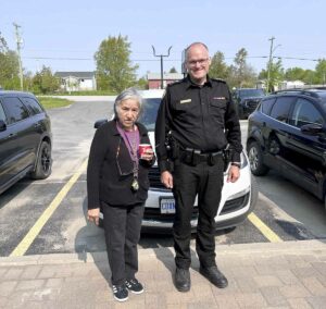 Marie Eshkabok-Trudeau joins Wiikwemkoong Tribal Police Service Acting Chief of Police Jason Spooner during the Coffee with a Cop event.